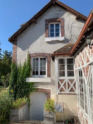 Pignon de la maison couvert de vigne vierge, véranda à colombages sur le côté