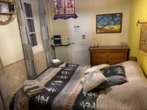 Chambre aux murs jaunes, lit double, lustre en verre coloré et tableau au mur