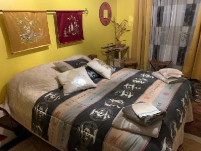 Chambre aux murs jaunes, lit double à parure grise à calligraphies, tentures brodées au mur