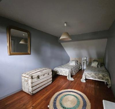 Chambre sous combles avec deux lits simples, malle ancienne et tapis rond tressé