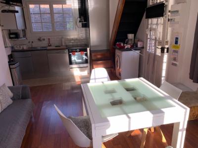 Séjour et coin cuisine du gîte vus depuis le canapé, table blanche au centre