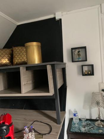 Coin salon devant un mur noir : console basse, coussins dorés et petits cadres au mur