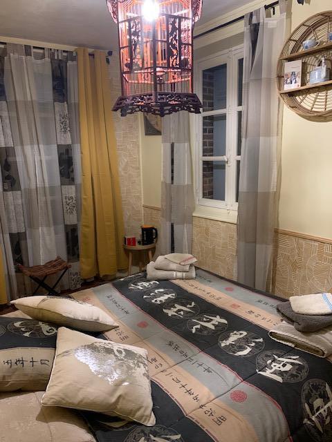 Chambre d'inspiration asiatique : lanterne en bois sculpté, rideaux clairs et couvre-lit à calligraphies